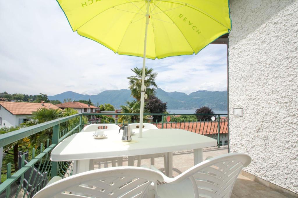 a table and chairs on a balcony with a yellow umbrella at Villa Laura in Germignaga