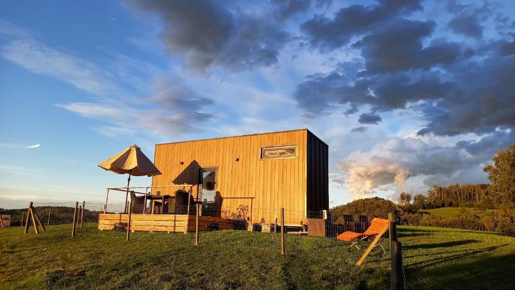 a yellow building with an umbrella on a field at Tiny House Auszeit in Nabegg