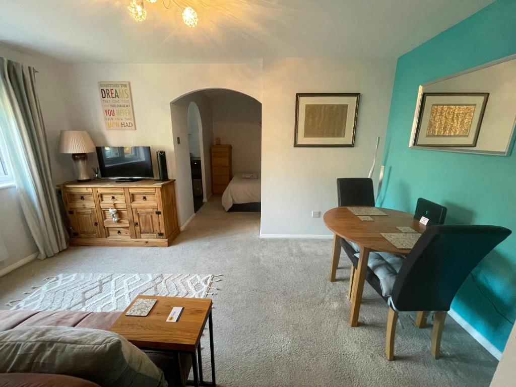 a living room with a bed and a table and a bedroom at Beautiful Peaceful Studio Flat in Waltham Abbey
