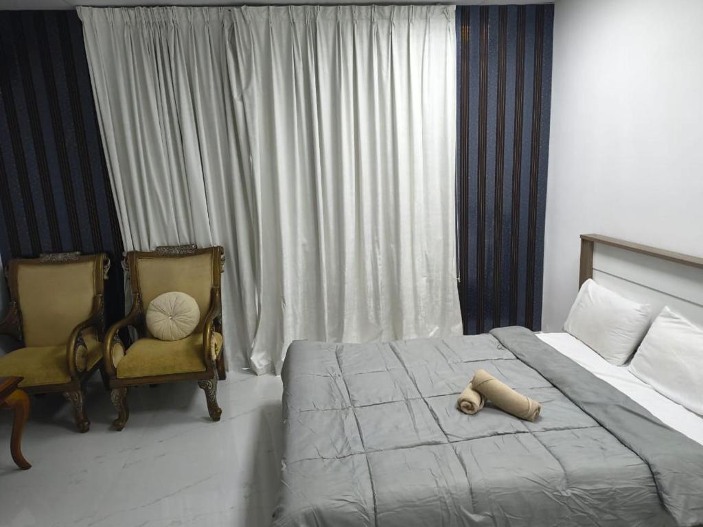 a bedroom with a bed and two chairs at Villa Laila in Sabkhah
