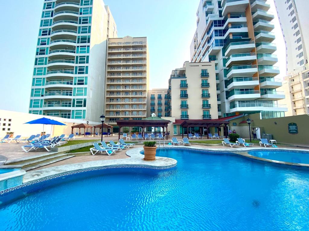 a swimming pool in a city with tall buildings at Astur Hotel & Residence in Veracruz