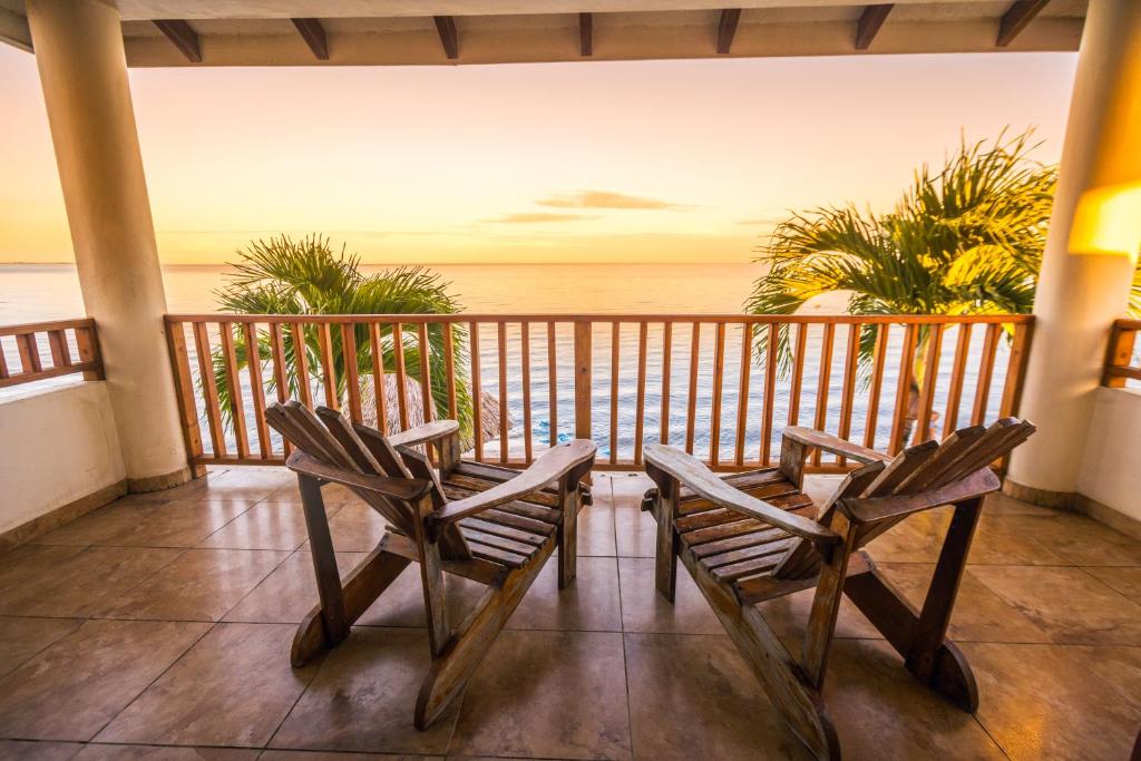 two chairs sitting on a balcony looking out at the ocean at Hopkins Bay Belize a Muy'Ono Resort in Hopkins