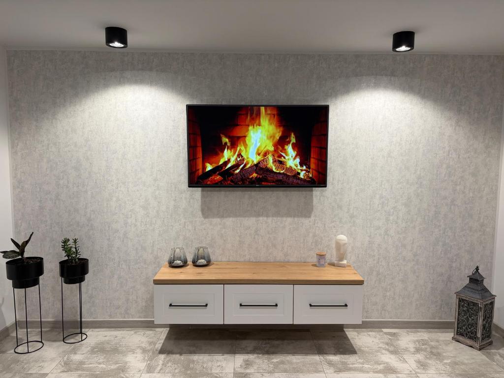 a room with a fireplace with a tv on the wall at Piękna Góra House in Gołdap