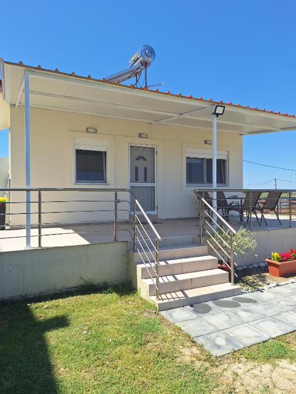 a house with stairs and a porch with a table at Sea Breeze House in Paralia Katerinis