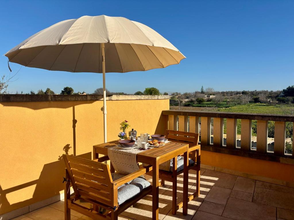 a wooden table with an umbrella on a balcony at Villa PARADISO - Tra Ulivi e Tramonti da Cartolina in Muro Leccese