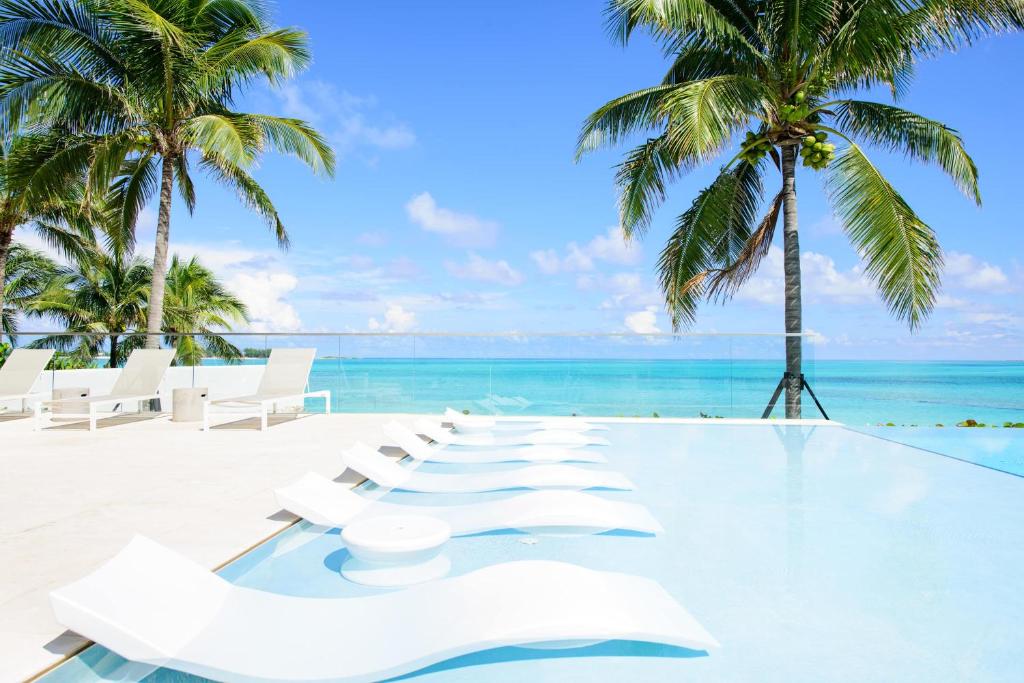 a row of white lounge chairs on the beach at One bedroom condo at ONE Cable Beach in Nassau