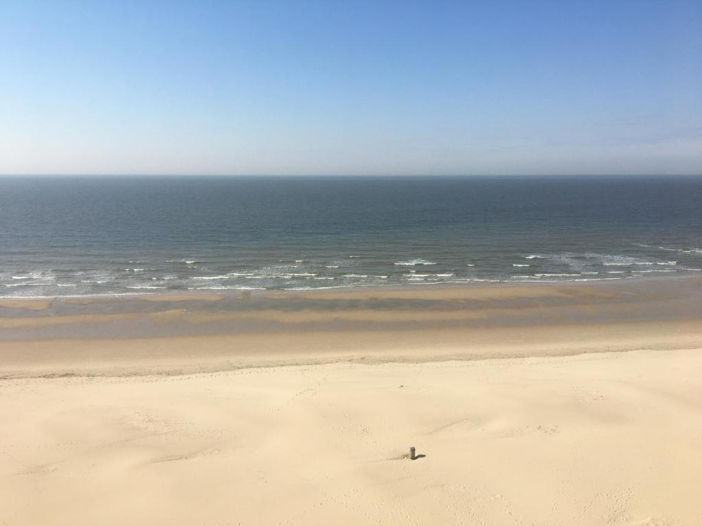a person is sitting on a beach near the ocean at Residentie Majestic in Middelkerke