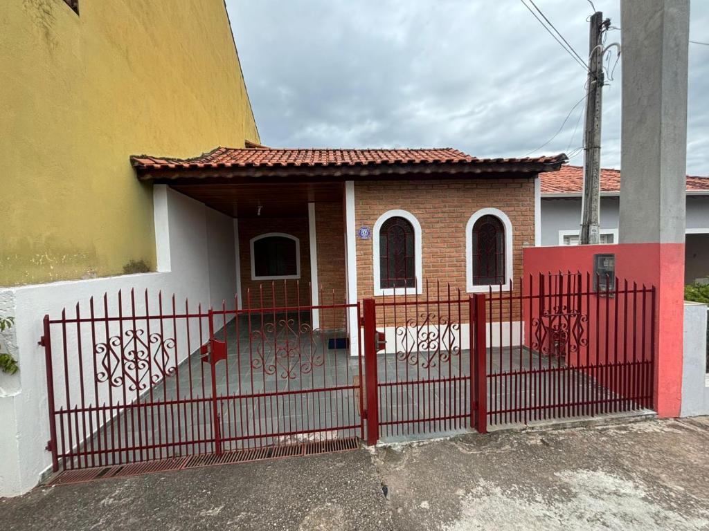 a red fence in front of a house at Casa Central Aconchegante in Cunha