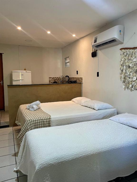 two beds in a room with a kitchen at Flat Praia do Pontal in Baía Formosa