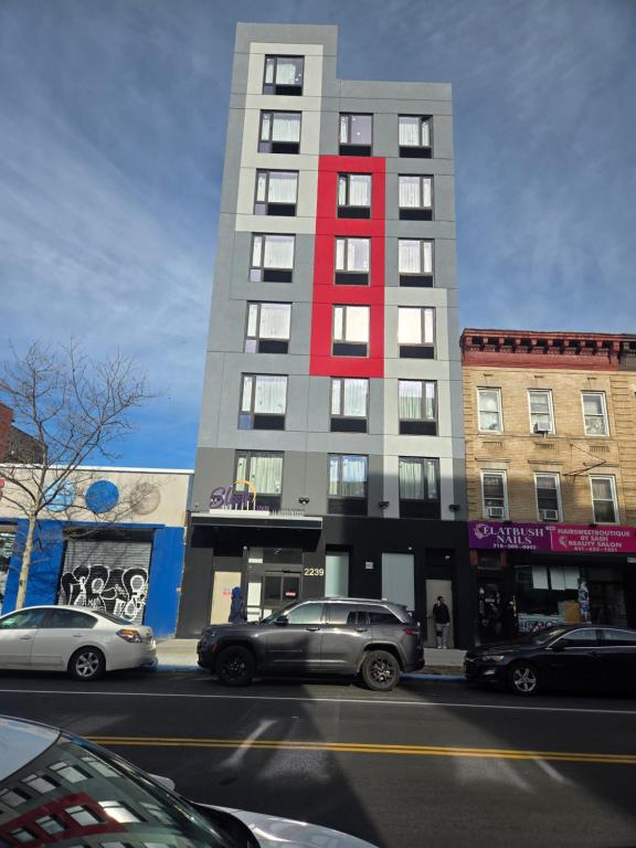 a tall building with cars parked in front of it at Sleep Inn in Brooklyn