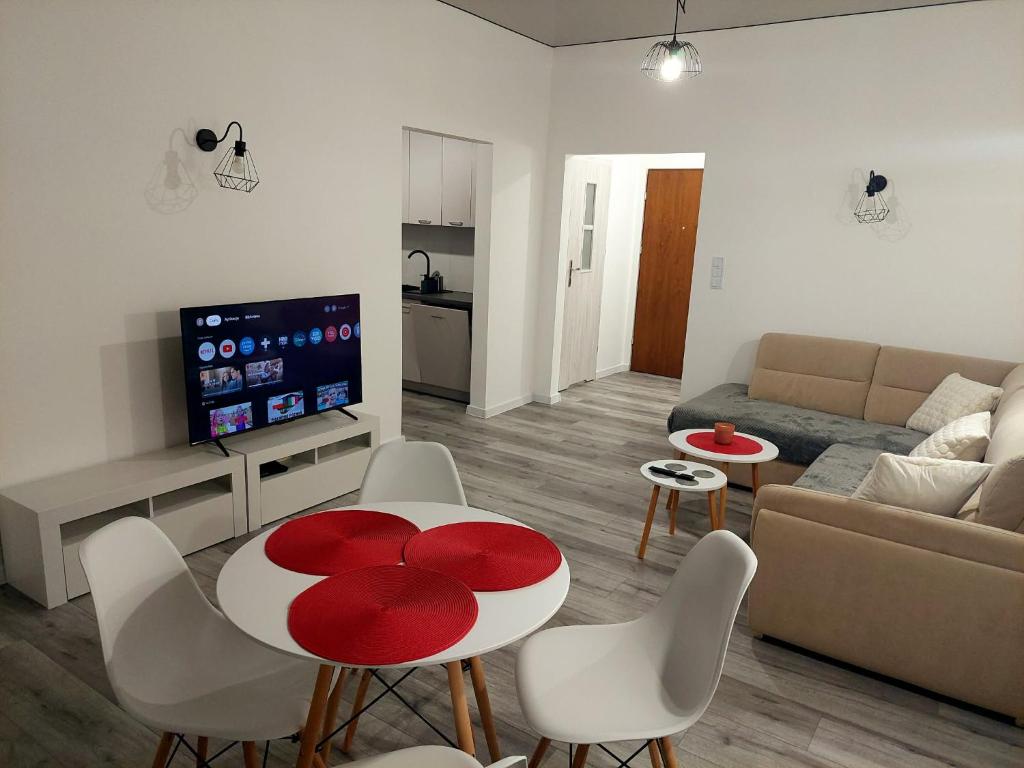 a living room with a red and white table and chairs at Beti's Apartment in Zambrów