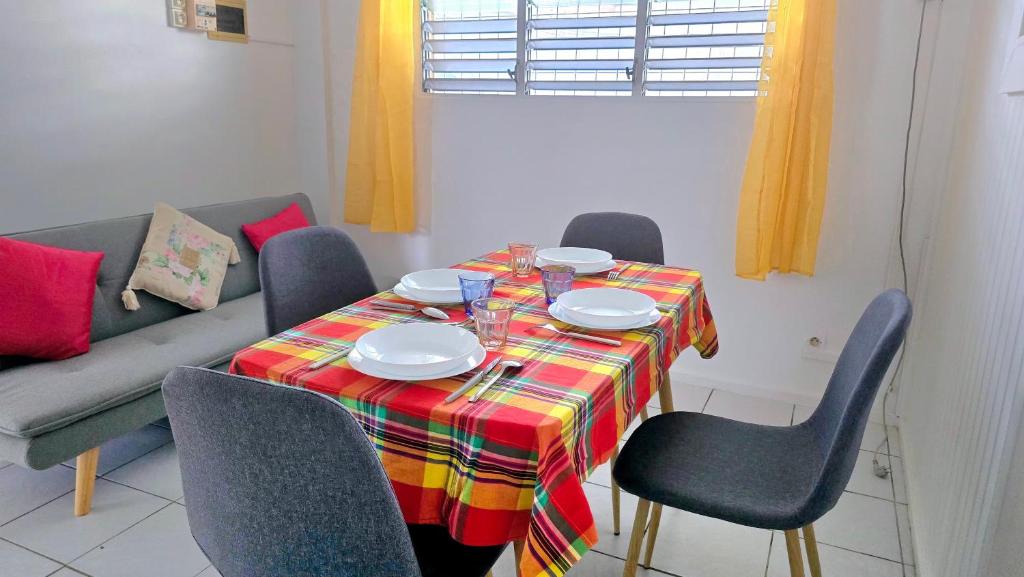 a dining room table with chairs and a couch at Logement meublé proche CHUM, idéal stagiaires et professionnels in Le Lamentin