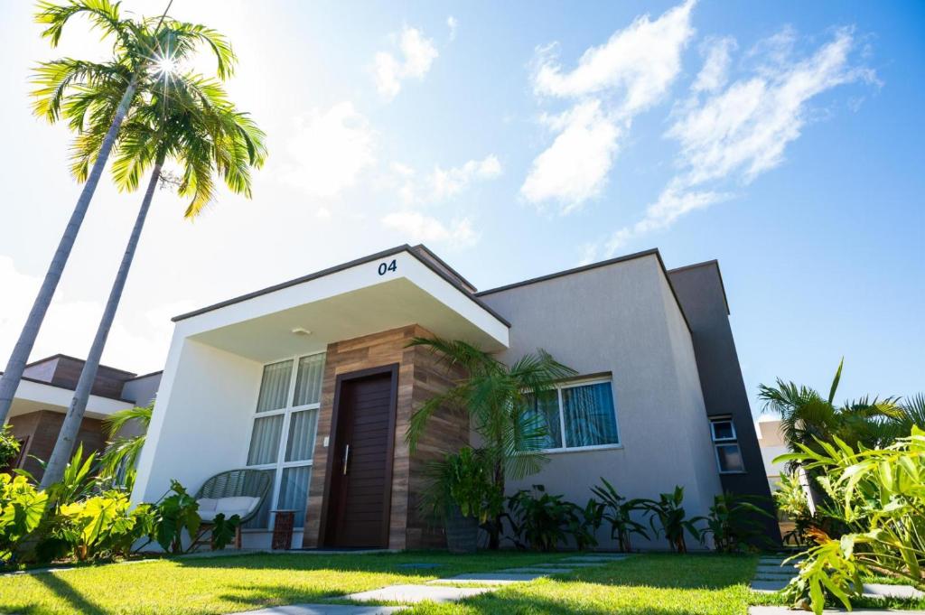 a house with palm trees in front of it at Chalé de Luxo com Piscina em Barra dos Coqueiros, Sergipe in Barra dos Coqueiros
