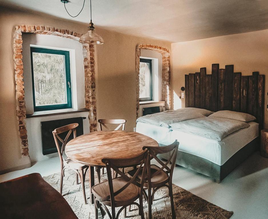 a bedroom with a bed and a table and chairs at Penzion Mezi lesy in Nové Hutě