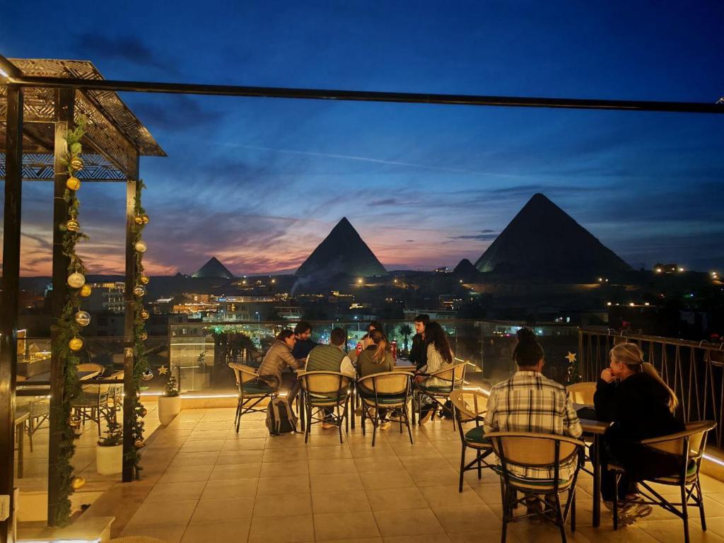 a group of people sitting at tables on a balcony with pyramids at Pyramids Spiritual Gate in Cairo