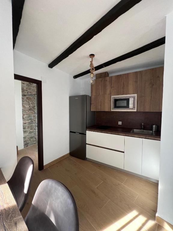 a kitchen with white cabinets and a black refrigerator at Villa Marín in Aroche