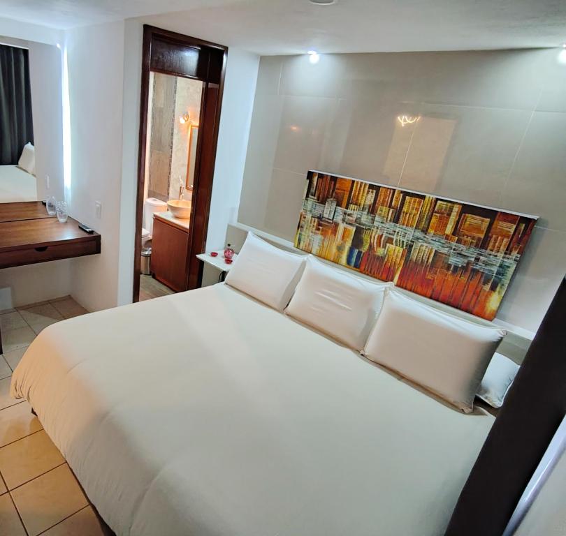 a bedroom with a large white bed with books on the wall at Posada Castillo in Zacatlán