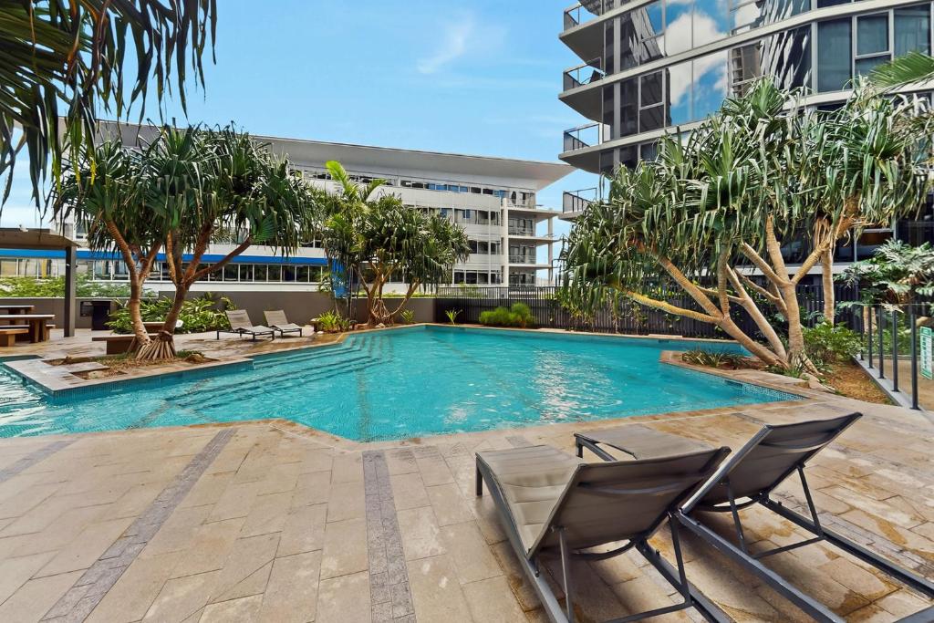 a swimming pool with two chairs and a building at Brisbane One Views Level 15 2BR Apartment in Brisbane