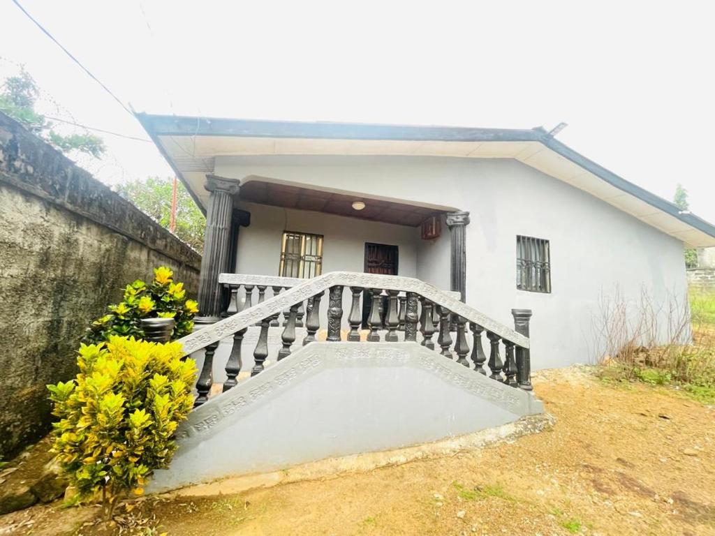 a white house with a balcony and some flowers at Brimelia Lodge in Bammbatuk