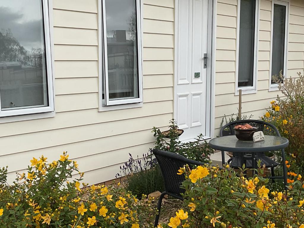 a table and chairs next to a house with flowers at D"s cottage - Self contained guest suite in Oatlands
