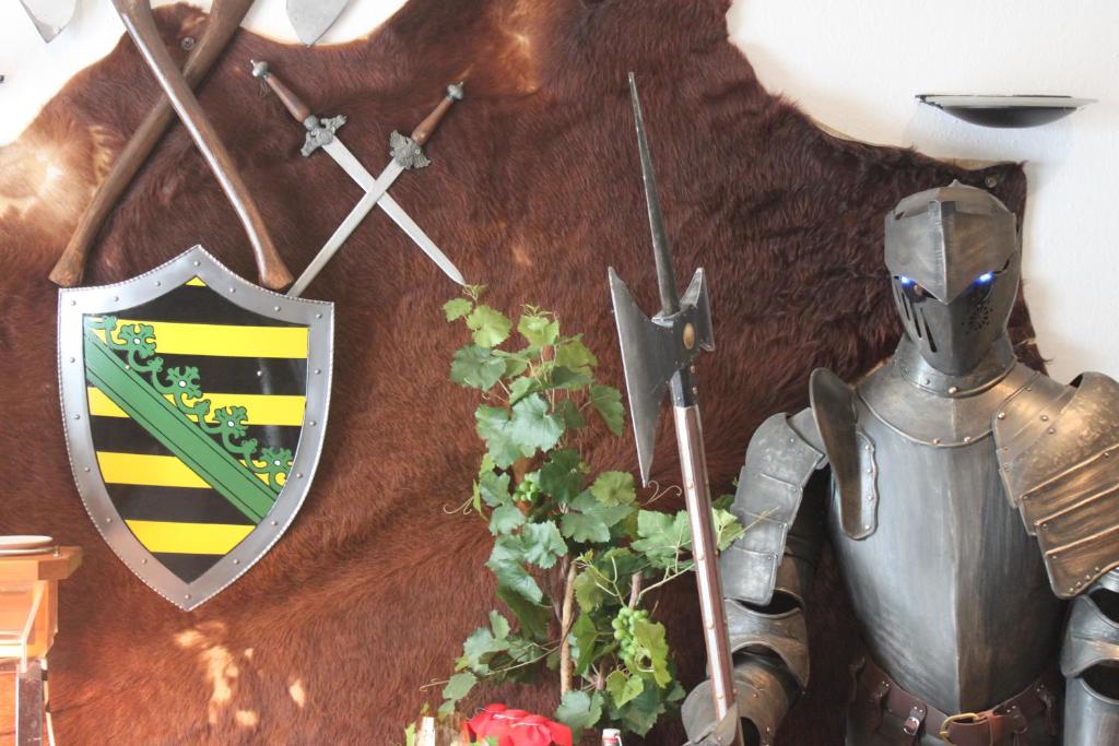 Un escudo en una pared con un caballero y una planta en Pension und Restaurant Die Burg, en Ehrenfriedersdorf