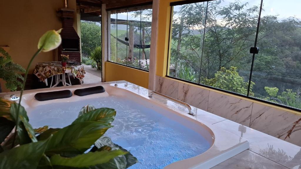 a bathroom with a bath tub with a large window at Sítio Ramos casa amarela in Cunha
