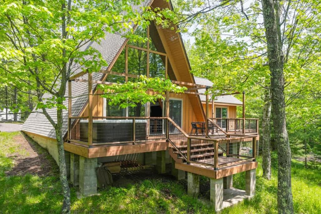 a house with a large deck in the woods at Tamarack Lodge Tomahawk WI in Lake Tomahawk
