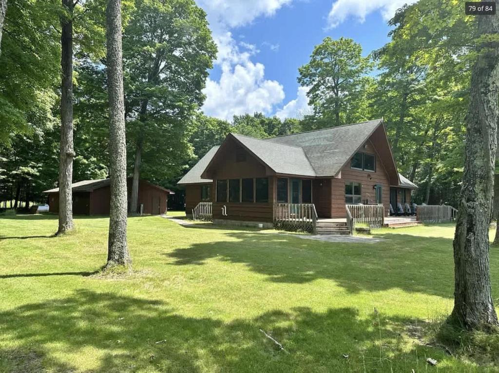 a log cabin in the middle of a yard with trees at Grace Place in Watersmeet