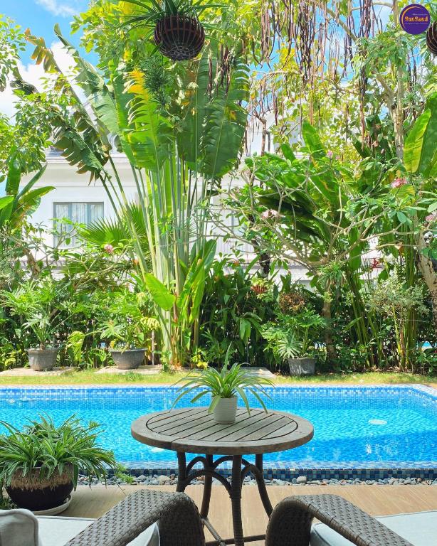 a table and chairs next to a swimming pool at LumiShora Villa - Bai Truong, Phu Quoc in Phú Quốc