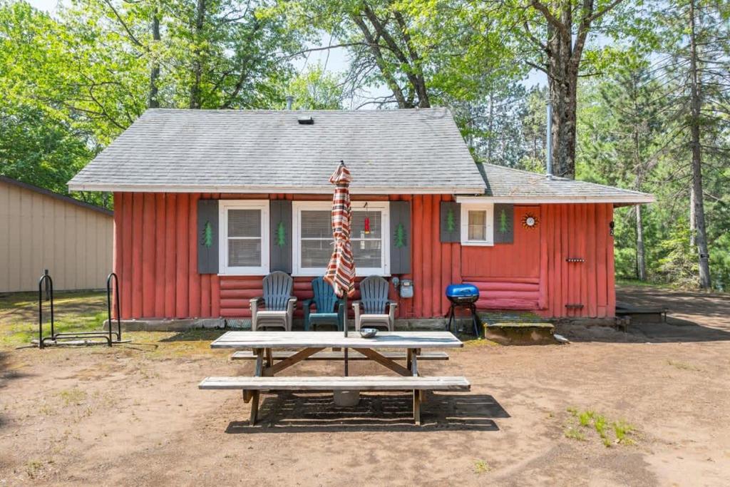 a red cabin with a picnic table in front of it at Loons Landing Legacy in Saint Germain