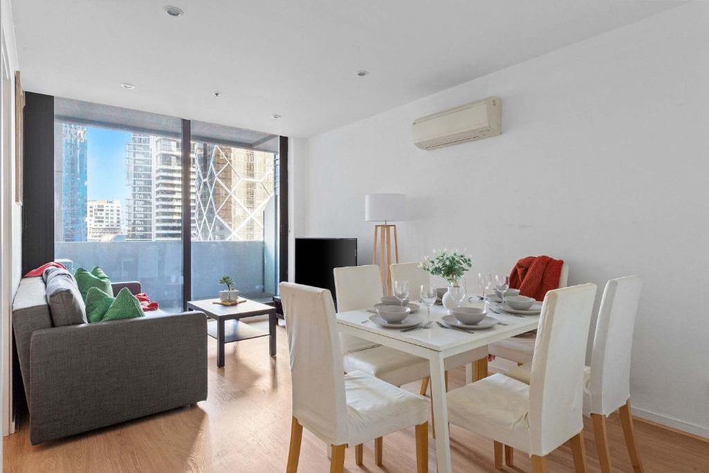 a dining room with a white table and chairs at Central 2BR Apt by Melbourne Central City Views in Melbourne