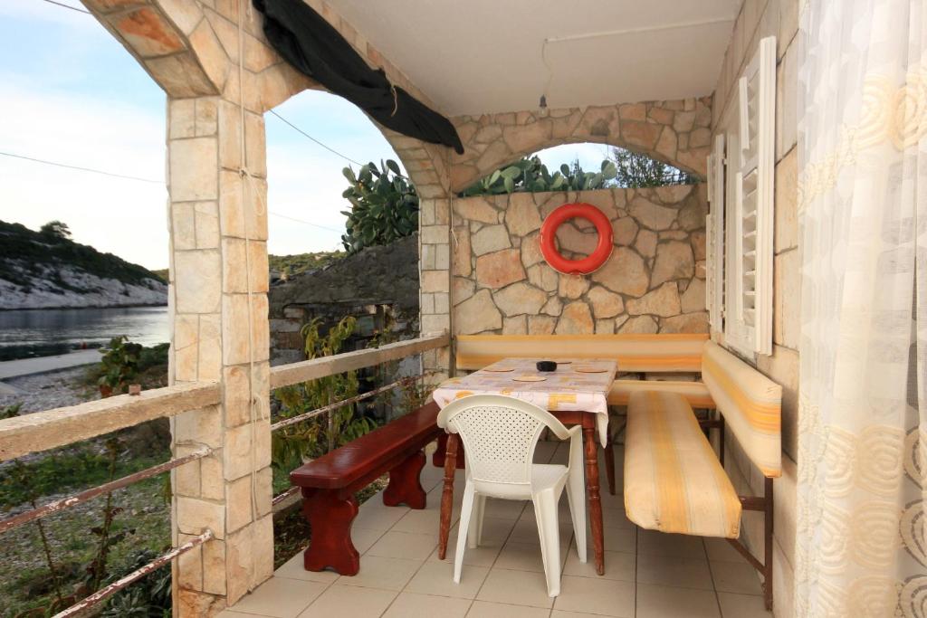 a patio with a table and chairs and a stone wall at Apartment Rogacic 2460b in Vis