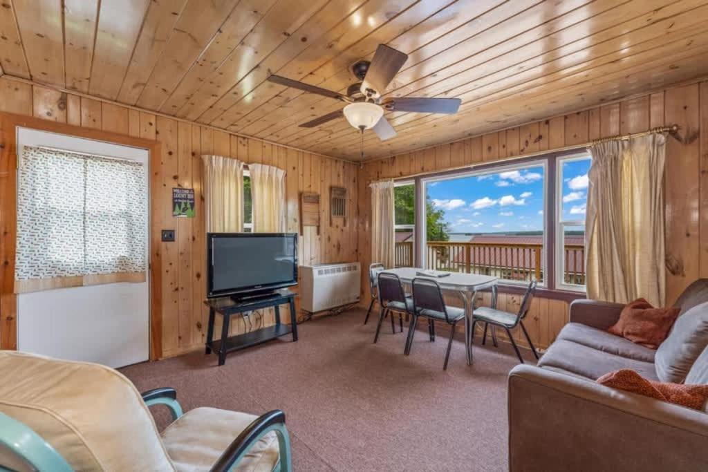 a living room with a television and a table with chairs at TB5 Thunder Bay Resort Cabin5 in Phelps