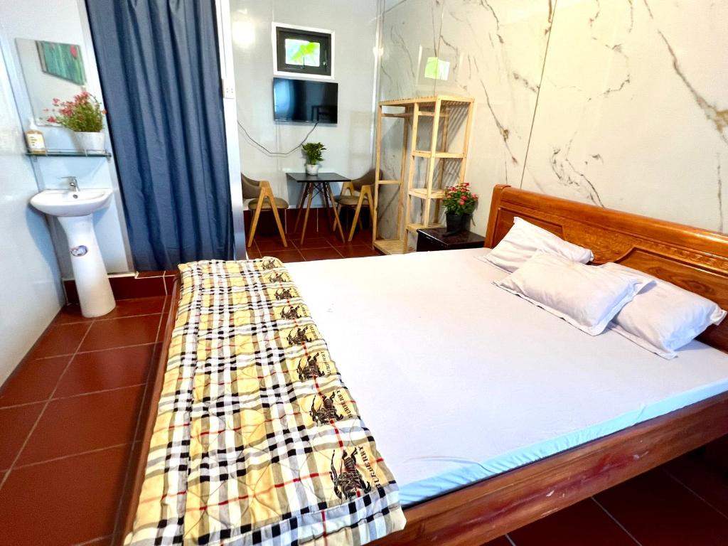 a bedroom with a bed with a plaid blanket on it at Khách Sạn LaMere Bến Tre in Ben Tre