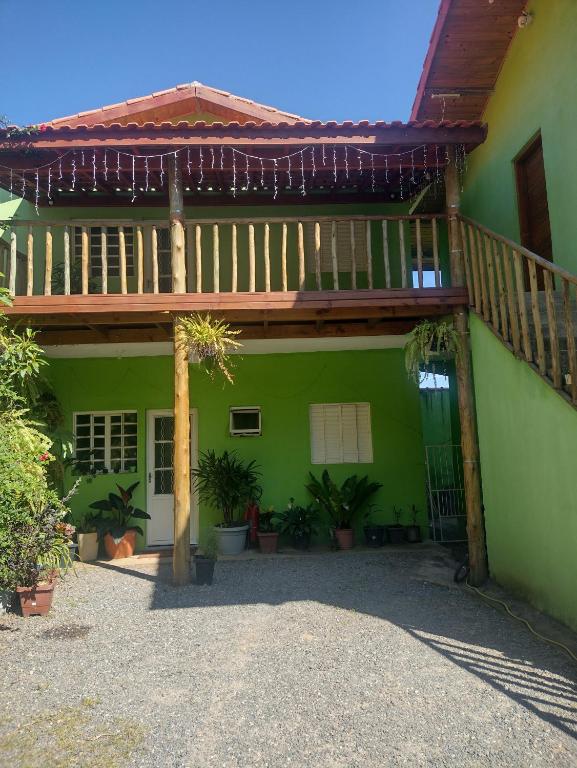 a green house with a wooden balcony and plants at chalé 8a 4 in Cunha