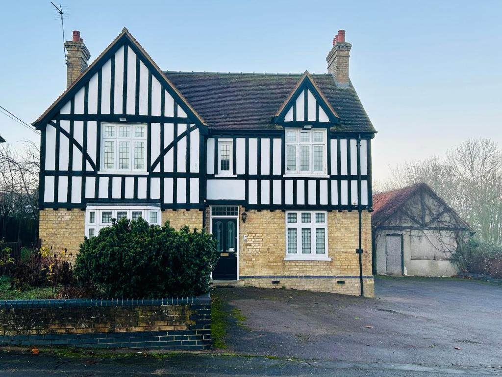 an old black and white house with a driveway at Rural boutique private flat in Bedford