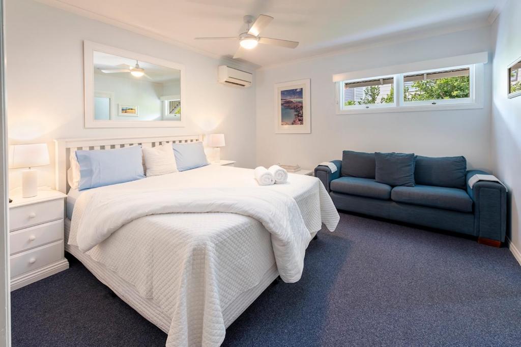 a bedroom with a large bed and a blue couch at Debbie's Place in Rainbow Beach
