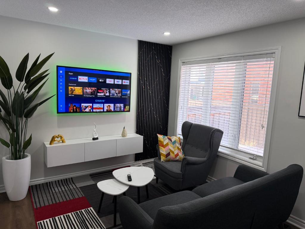 a living room with a couch and a tv on a wall at Cozy Private Two-Level Suite In Brampton With Separate Entrance And Living Area on Main Floor in Brampton