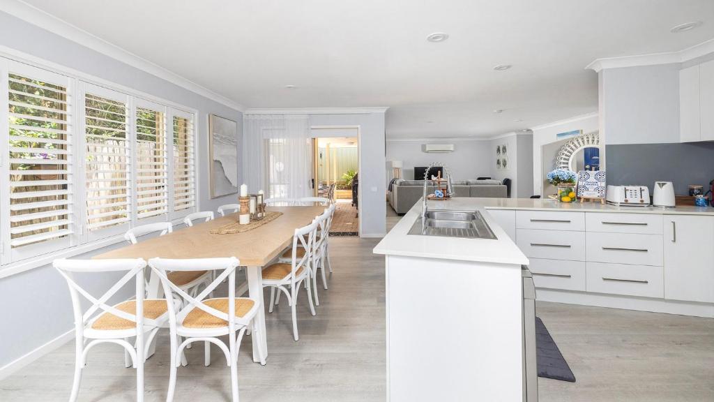 a kitchen with a long table and white cabinets at Serenity in Corlette