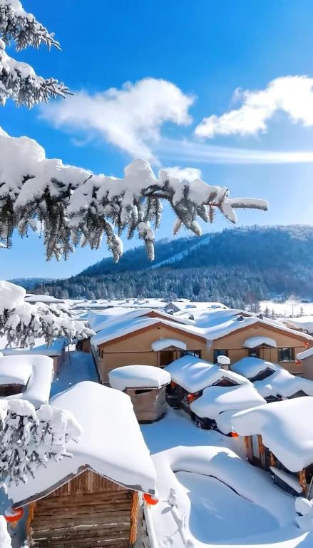 a winter view of a resort with snow covered roofs at Snow Valley Ma Hua Inn in Wuchang