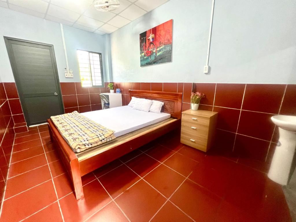 a small bedroom with a bed and a night stand at La Mera Homestay in Ben Tre