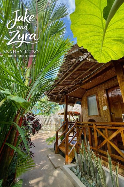 a small hut with a thatched roof in a garden at Jake and Zyra Place in San Vicente