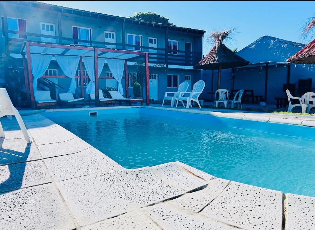 a swimming pool with chairs and a building at Complejo Brisas del Mar in San Bernardo