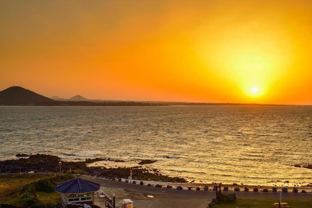 a sunset over the ocean with a group of people at Udo Daol Pension in Jeju