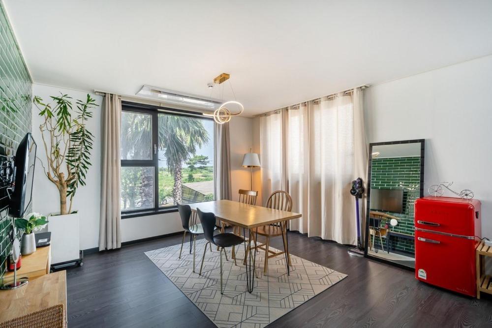 a dining room with a table and chairs and a red refrigerator at Jeju Aromtarom House in Jeju