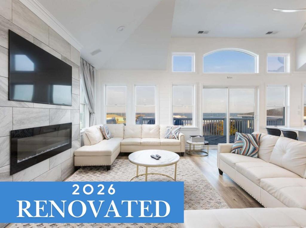 a living room with white furniture and a tv at Nags Head Oceanfront Private Beach Access & Pool in Nags Head