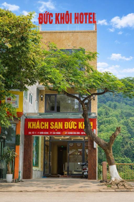 a blue kotin hotel with a tree in front of it at Đức Khôi Hotel in Cao Bằng