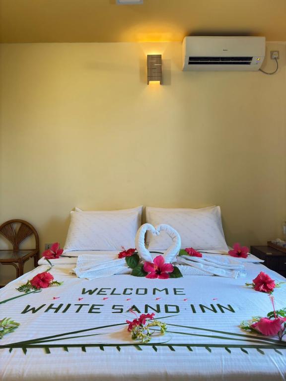 a bed with a wedding sign and flowers on it at White Sand Inn in Maamigili