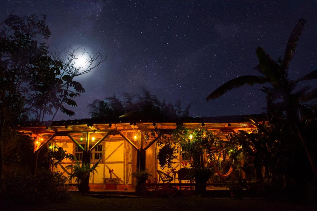 a house lit up at night with a full moon at Centro Holístico Allpa Samay in Estación El Salto