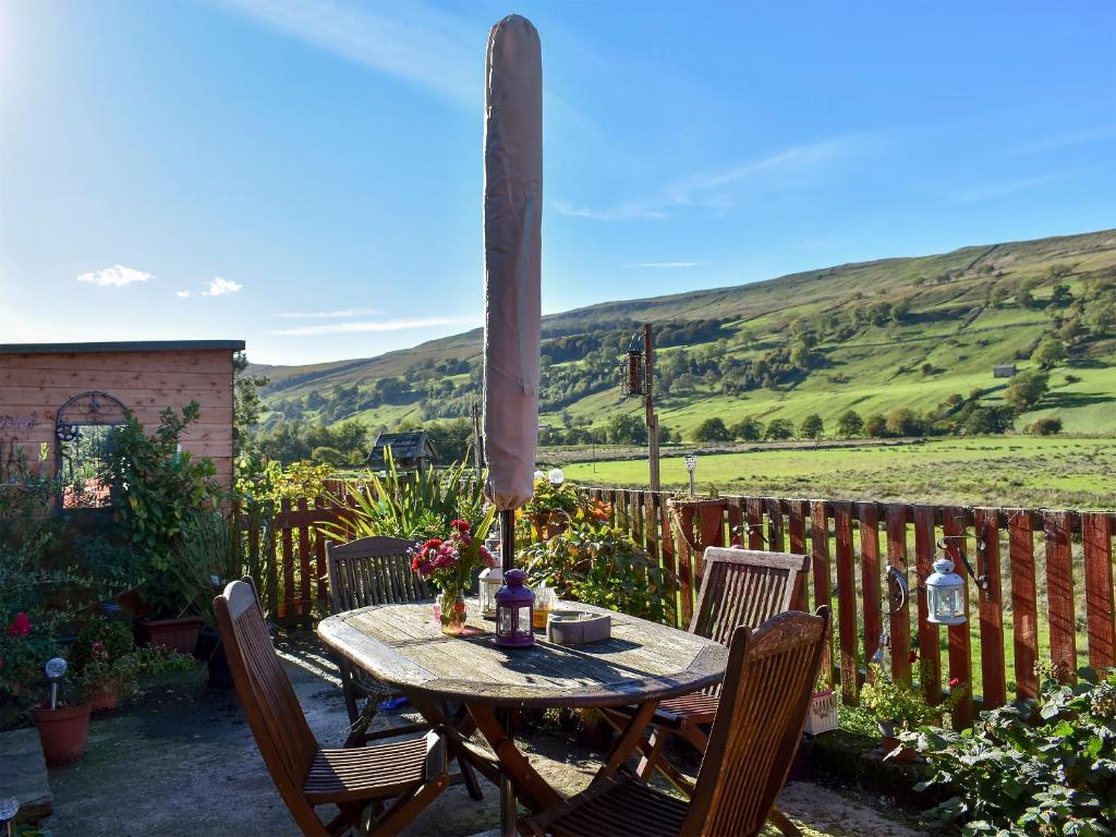 a wooden table with chairs and a table with flowers on it at Mystified Bungalow in West Burton